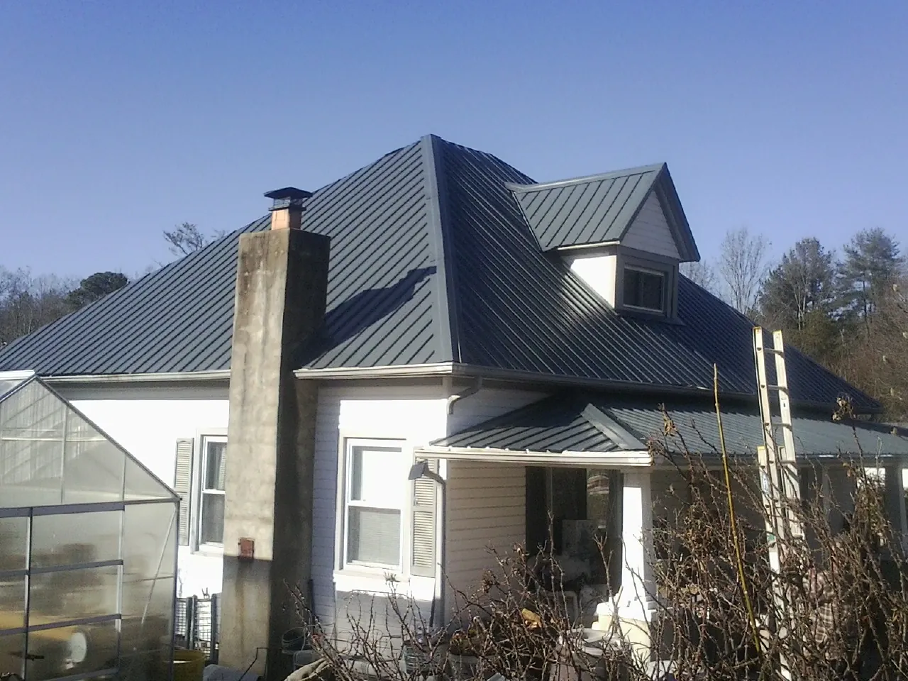 Dark blue standing seam metal roof on a white farmhouse with dormer — Slate & Tile Roof Repair by Roofing Brothers in Kent City