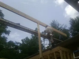 Carpenter setting a ridge beam over a new addition frame — Ice Dam Removal by Roofing Brothers in Kent City