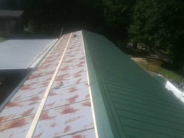 Old rusted panels beside newly installed green metal roofing — Wind Damage Roof Repair by Roofing Brothers in Kent City