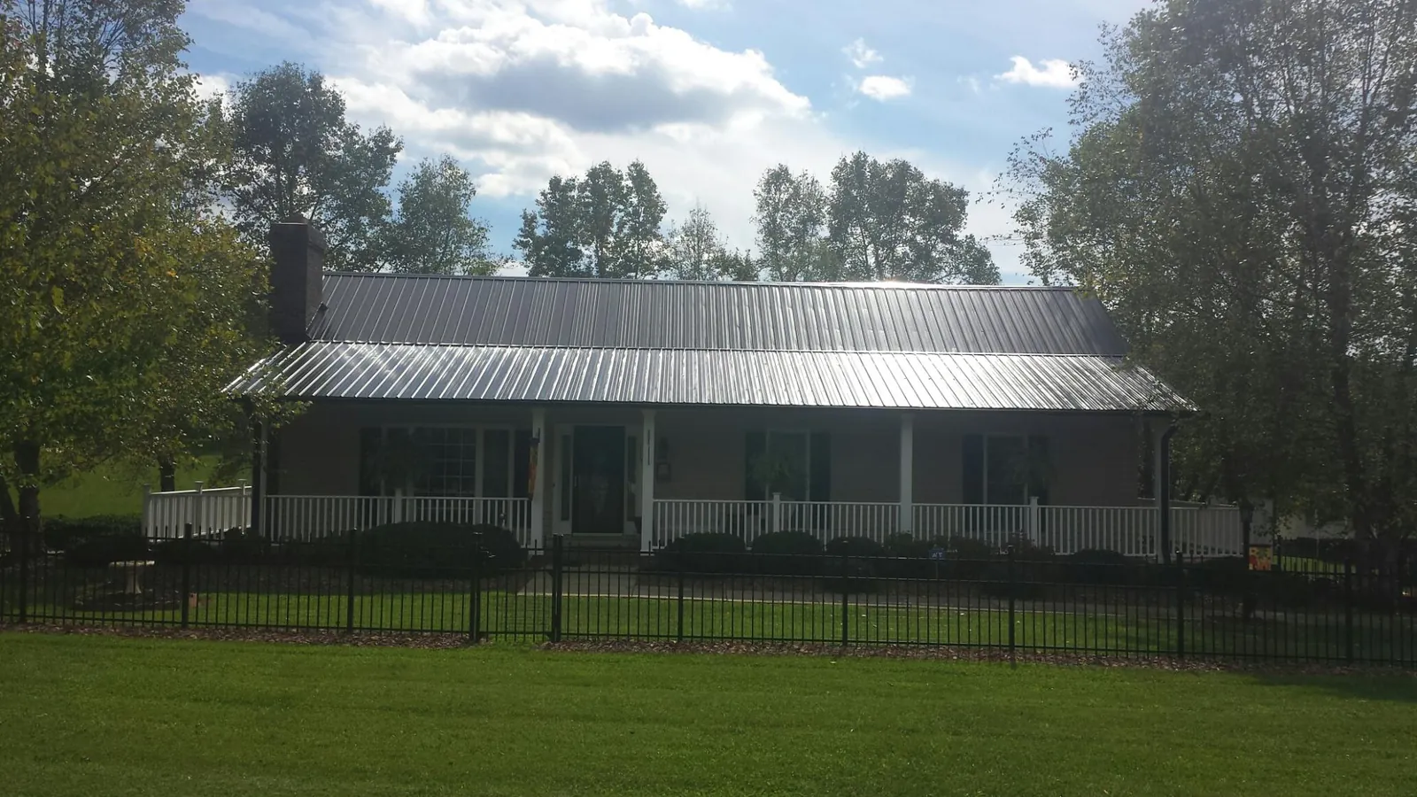 Gray metal roof on a brick ranch with a full width front porch — Gutter Guard Installation work by our crew in Kent City