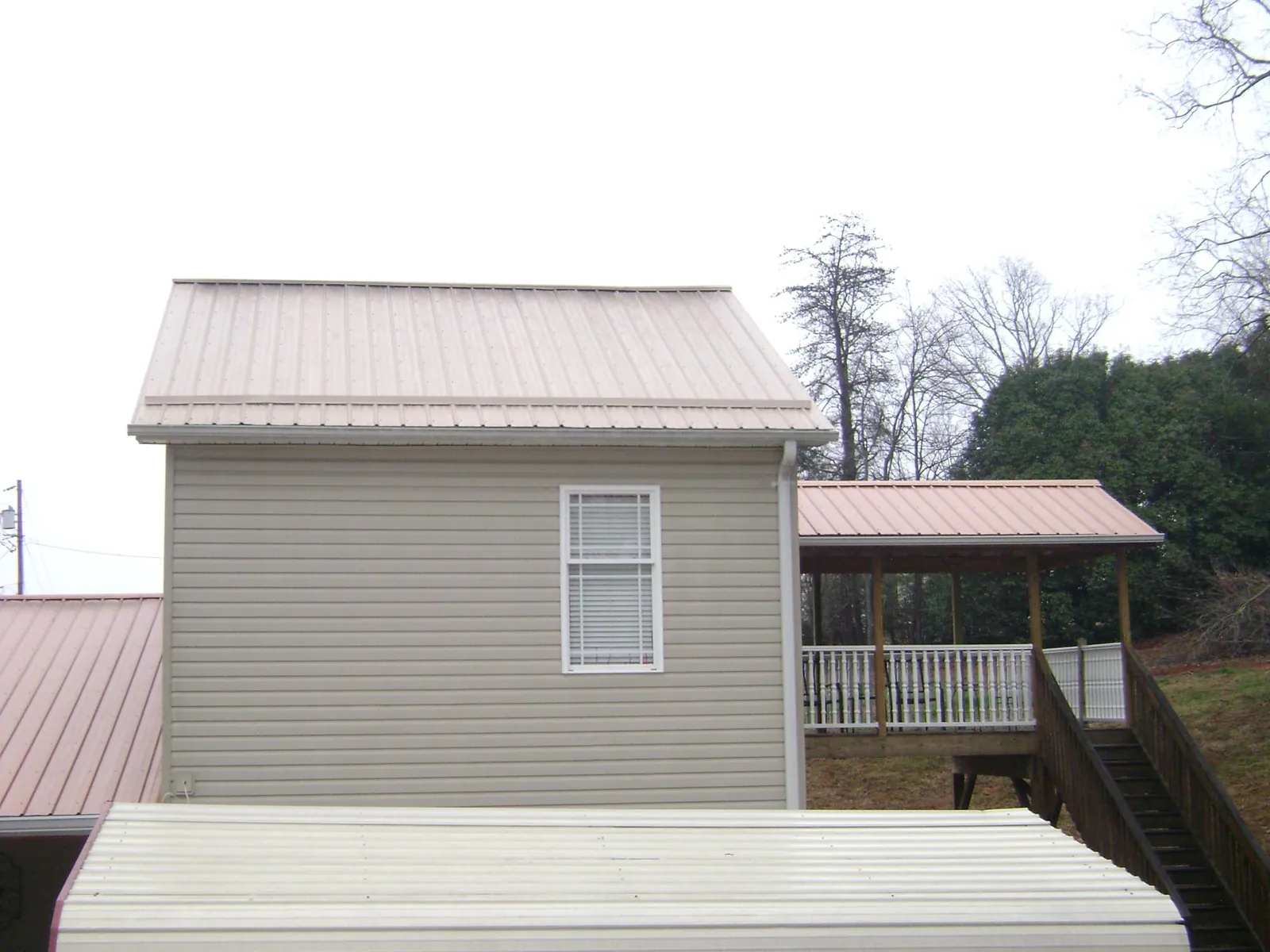 Tan metal roofs on a two story addition and attached porch, from a Roof Replacement job in Kent City