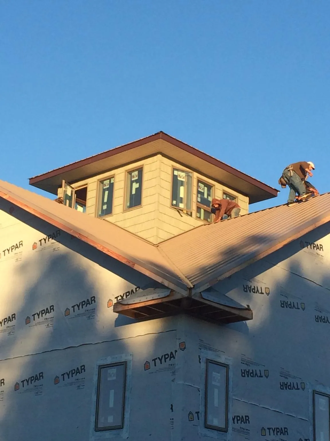 Roofers working around a rooftop cupola on a new metal roof at sunset — Roof Waterproofing in Kent City by Roofing Brothers